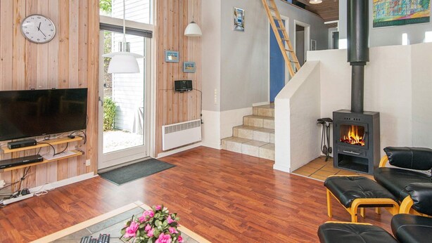 Un vaste salon doté d’un plancher en bois, d’un téléviseur à écran plat, d’une cheminée et d’un escalier menant à un niveau supérieur.