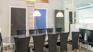 Un espace repas doté d’un plafond haut, de poutres en bois et d’une porte bleue.