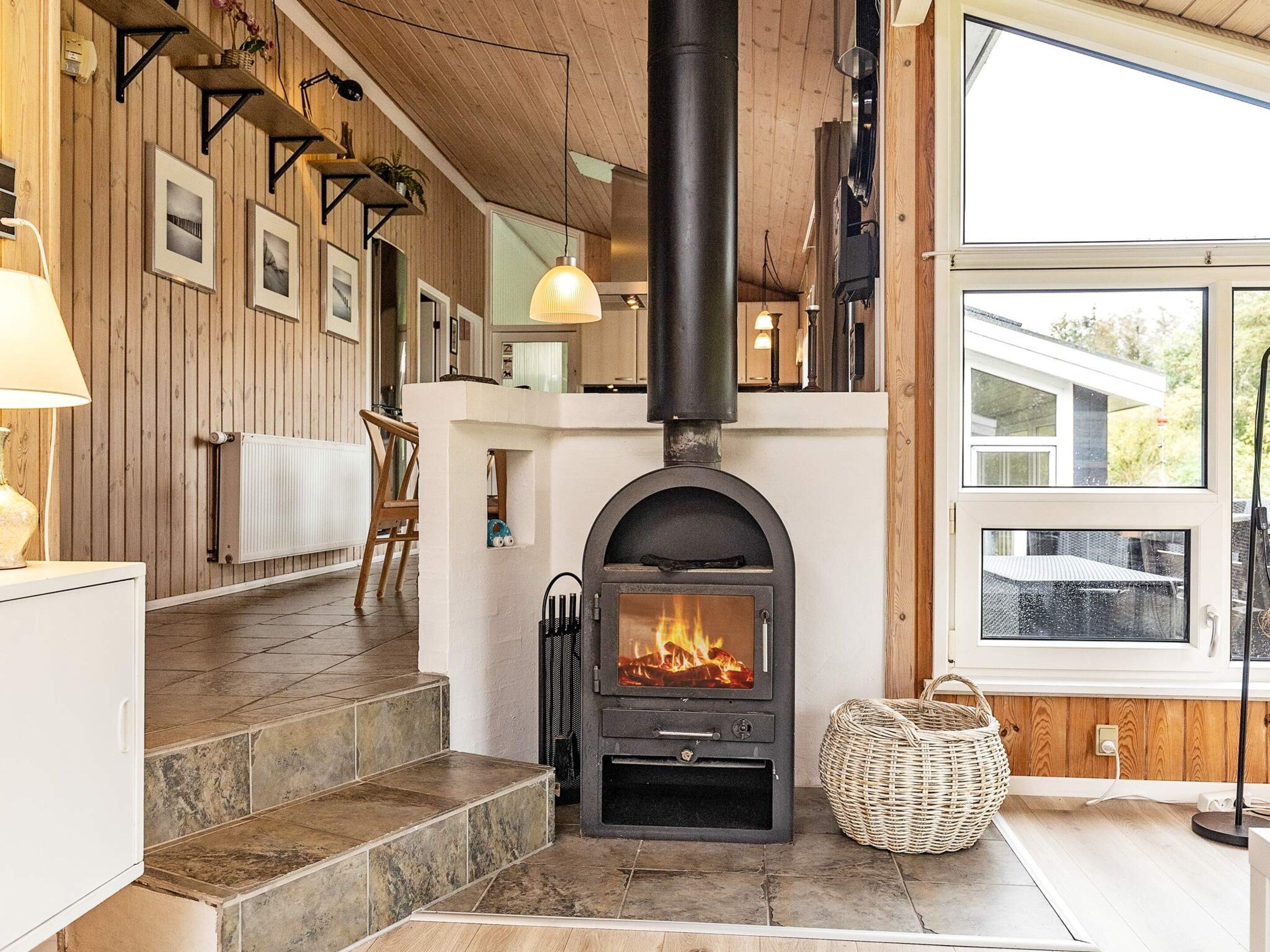 A modern interior with a fireplace, wooden walls, and a view through large windows.