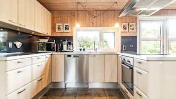 A modern kitchen with wooden cabinets, stainless steel appliances, and a large window providing natural light.