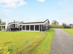 A modern house with a large glass extension, a gravel driveway, and a fenced garden area. - 4 Star Holiday Home in Hjorring (Hjørring)