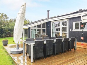 A covered outdoor seating area with a table and chairs, a large umbrella, and a potted plant. - 5 Star Holiday Home in Hjorring (Hjørring)