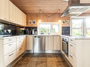 Une cuisine moderne avec des meubles en bois, des appareils électroménagers en acier inoxydable et une grande fenêtre qui laisse entrer la lumière naturelle.