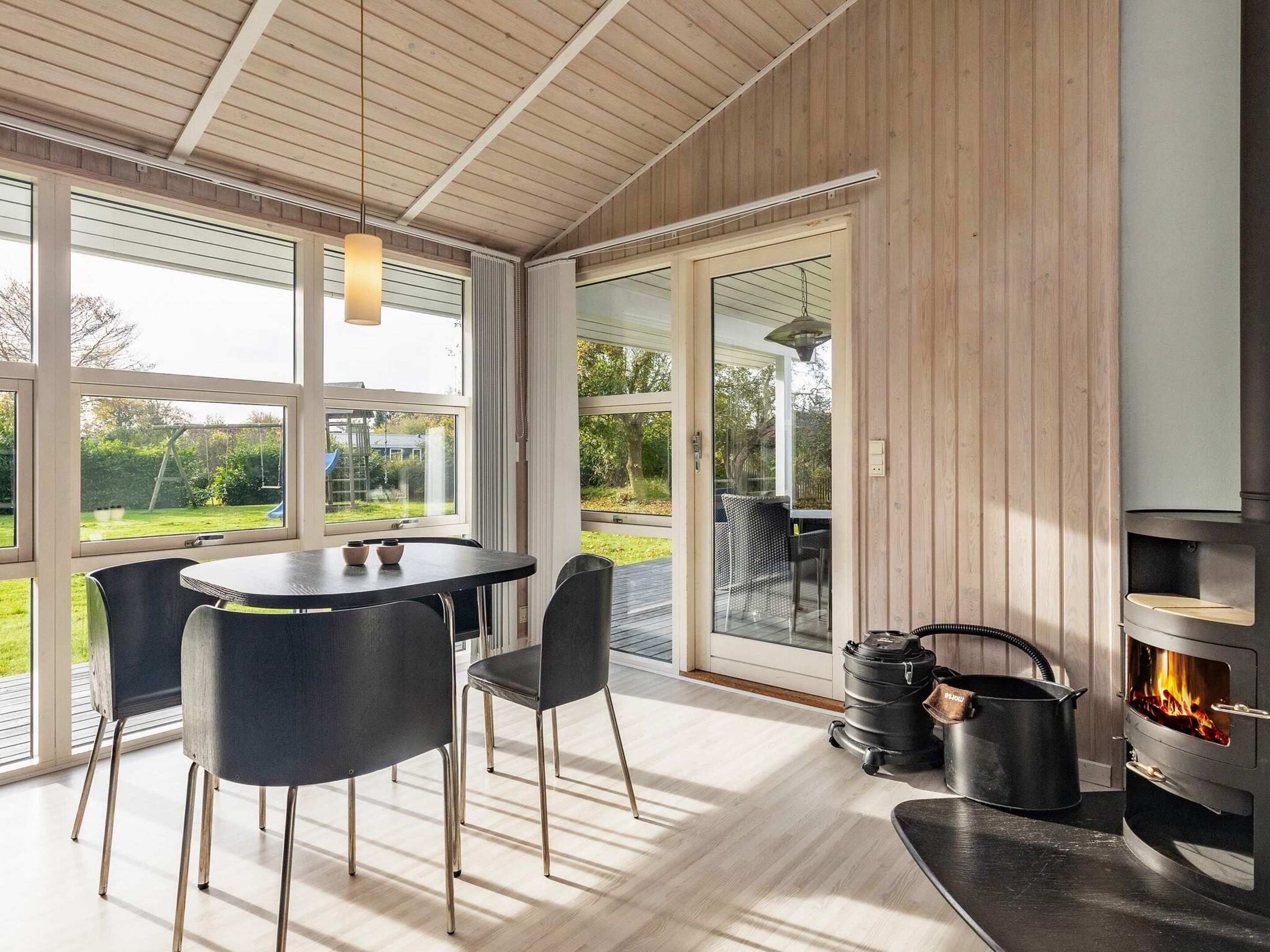 Une cuisine moderne avec un mur lambrissé en bois, une cuisinière encastrée et un coin repas comprenant une table et des chaises.