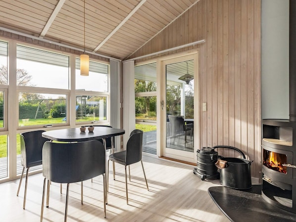 A modern kitchen with a wood-paneled wall, a built-in stove, and a dining area with a table and chairs.