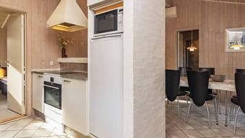 A modern kitchen with a microwave, oven, and dining area with chairs and a table.
