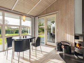 Eine moderne Küche mit Holzvertäfelung, einem Einbauherd und einem Essbereich mit Tisch und Stühlen.