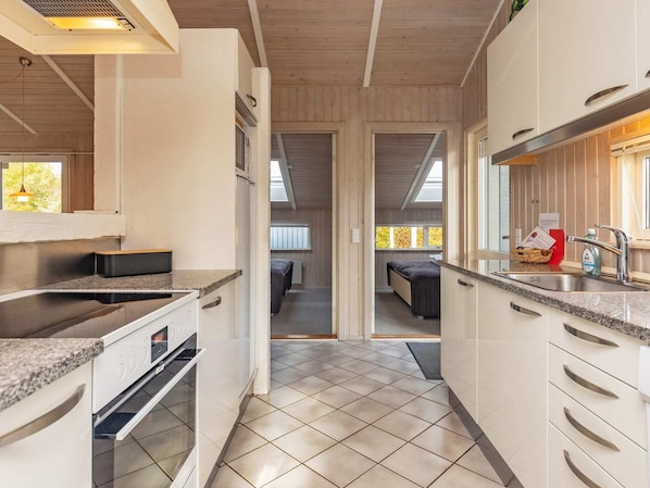 A compact kitchen with a built-in oven, a sink, and a breakfast bar.