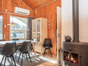 A cozy cabin interior with a dining area, a wooden cabinet, a stove, and a window with curtains. - 4 Star Holiday Home in Juelsminde (Horsens)
