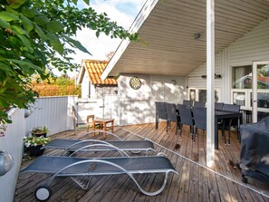 A covered outdoor patio with a table and chairs, a dartboard, and a wooden deck. - 4 Star Holiday Home in Juelsminde (Horsens)