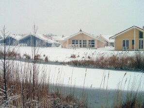 A row of buildings with a flat roof, a clear sky, and a frozen body of water in the foreground. - Holiday Home in Otterndorf (Otterndorf)