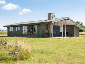 A modern house with a large open patio, a chimney, and a large window.