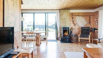 A cozy living room with a fireplace, wooden furniture, and a large window.