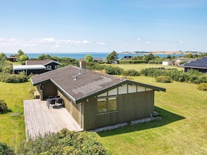 A single-story building with a sloped roof, a deck, and a view of the sea. - 7 Person Holiday Home in Knebel (Knebel)
