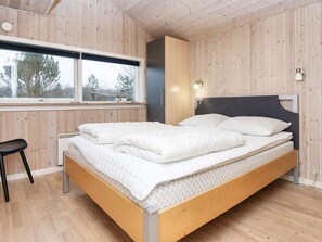 A bedroom with a wooden bed, a window, and a desk.