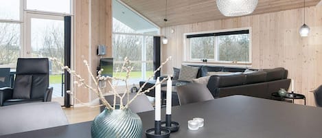 A modern interior with a large dining table, a sofa, and a TV.