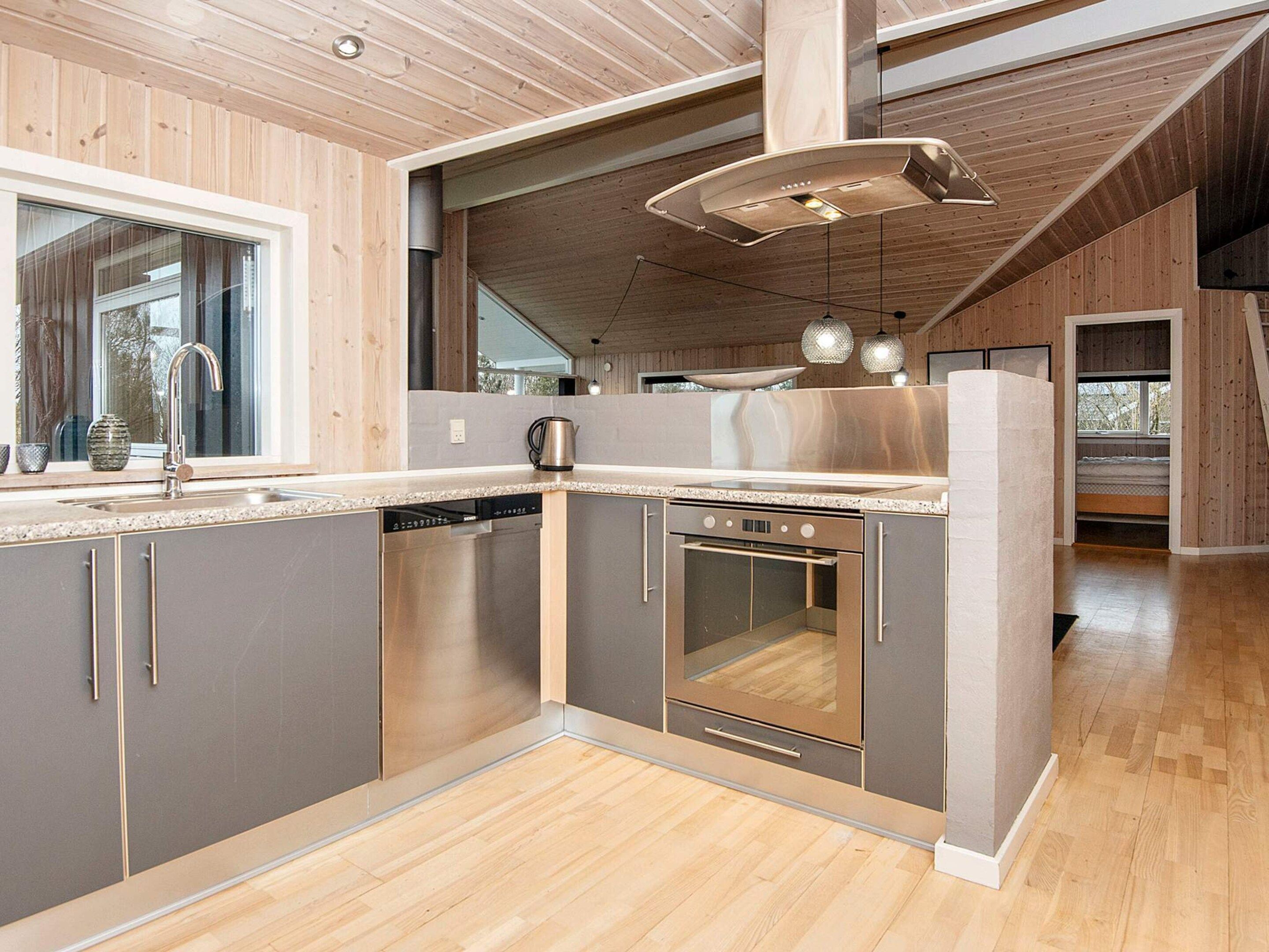 Una cocina moderna con horno empotrado, electrodomésticos de acero inoxidable y techo de madera.