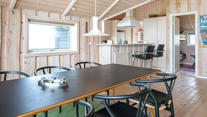 A wooden interior with a dining table, chairs, a hanging light fixture, and a window. - 7 Person Holiday Home in Harboore-by Traum (Harboore)