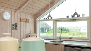 A kitchen with wooden walls, a window with a view, a sink, and a dishwasher. - 7 Person Holiday Home in Harboore-by Traum (Harboore)