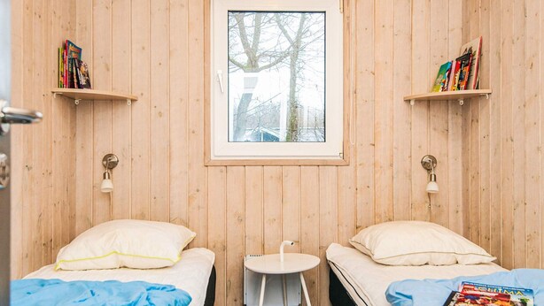 A small, cozy room with two beds, a small table, and a window.