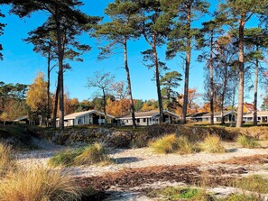 A row of cabins with a natural landscape, including trees and shrubs. - 4 Star Holiday Home in Nexo (Nexø)