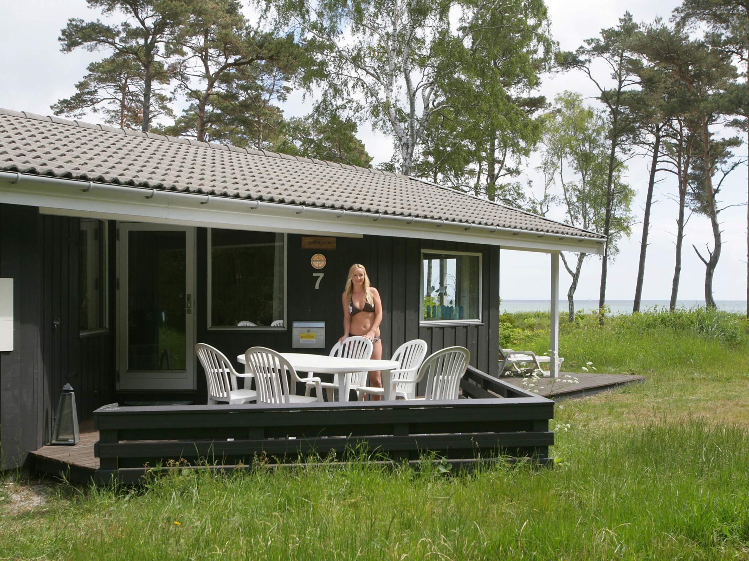 Une cabane dotée d’une terrasse, de meubles de jardin et offrant une vue sur la mer.