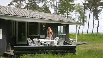 Une cabane dotée d’une terrasse, de meubles de jardin et offrant une vue sur la mer.