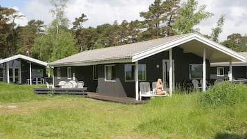En toetages hytte med veranda, udendørs siddepladser og en terrasse.