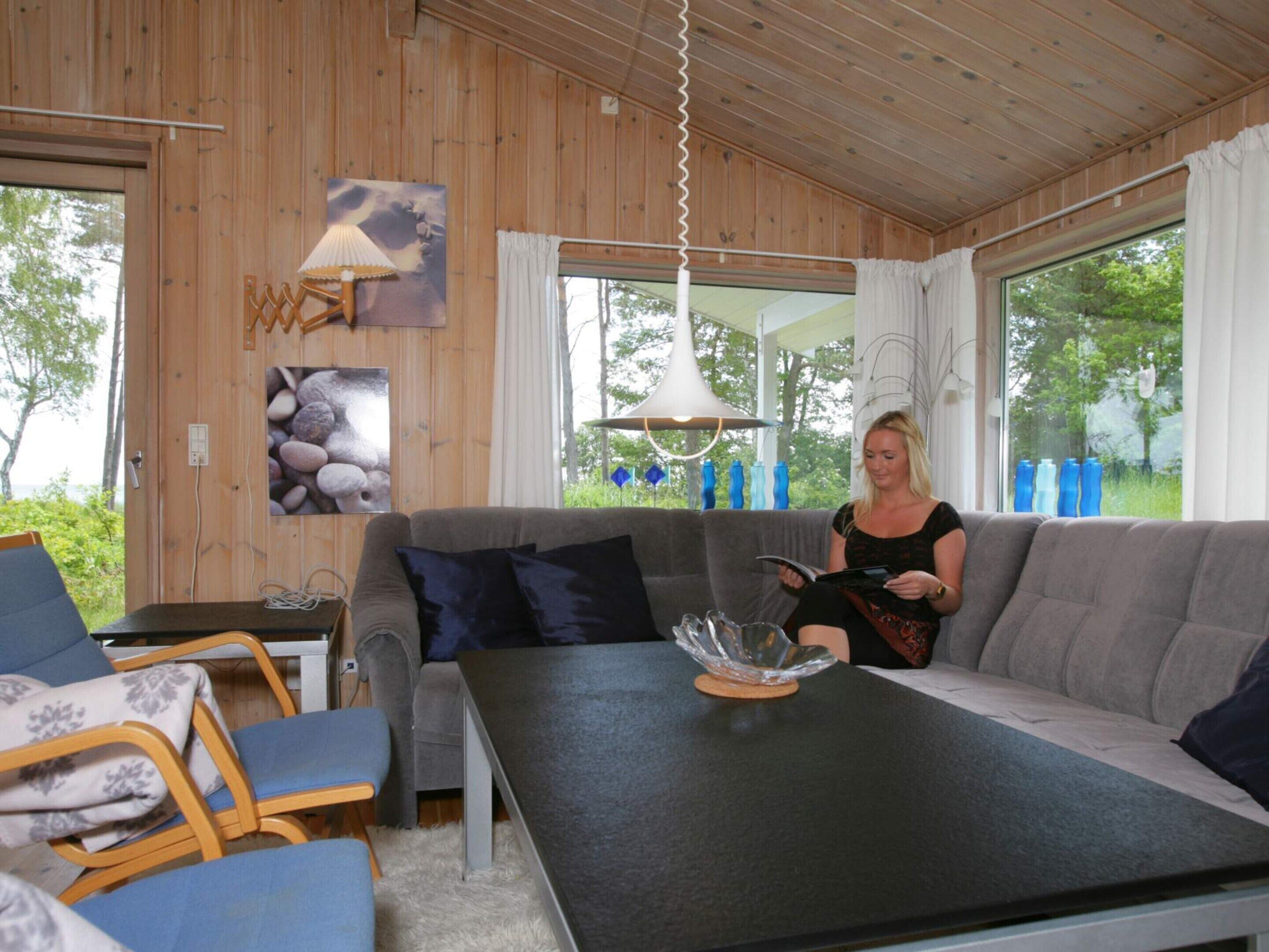 Et hyggeligt værelse med en grå sofa, et bord med en glaskåle og en lampe.