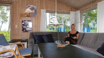 Et hyggeligt værelse med en grå sofa, et bord med en glaskåle og en lampe.