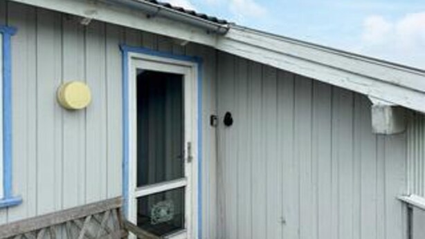 A building with a white exterior, a blue door, and a small porch with a wooden railing. - 12 Person Holiday Home in Hjorring (Hjørring)
