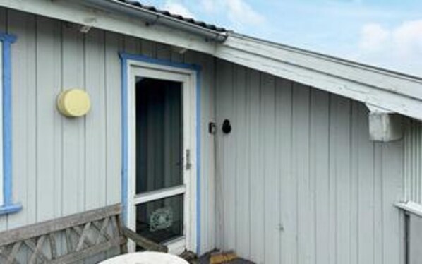 A building with a white exterior, a blue door, and a small porch with a wooden railing.