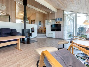 A modern living room with a fireplace, a flat-screen TV, and a dining area with wooden furniture.