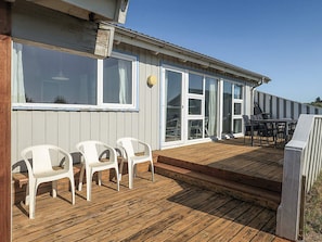 A wooden deck with outdoor furniture, a covered patio area, and a building with large windows and doors. - 12 Person Holiday Home in Hjorring (Hjørring)