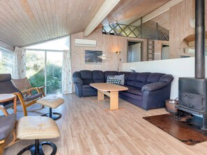 A cozy living room with a sofa, chairs, a table, and a wood-burning stove. - 12 Person Holiday Home in Hjorring (Hjørring)