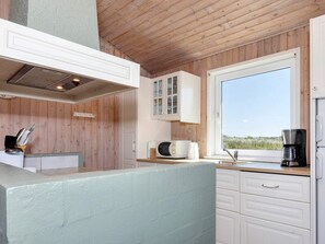 A modern kitchen with wooden walls, a large window, and a view of the outdoors. - 12 Person Holiday Home in Hjorring (Hjørring)