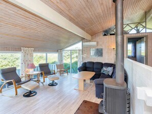 A modern living room with a sofa, chairs, a table, and a wood-burning stove. - 12 Person Holiday Home in Hjorring (Hjørring)
