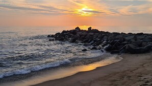 A beach with a rocky breakwater, waves, and a sunset. - 4 Person Holiday Home in Lemvig (Lemvig)