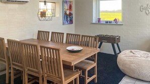 A dining area with a wooden table and chairs, a window with a view of a field, and a wall-mounted air conditioner. - 4 Person Holiday Home in Lemvig (Lemvig)