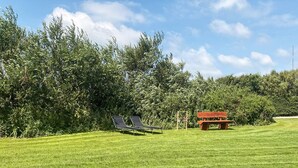 A grassy area with two lounge chairs and a small red structure.