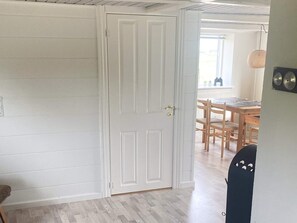 A room with a white door, wooden flooring, and a dining area with a table and chairs.