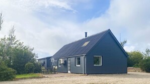 Un bâtiment d’un seul étage, doté d’un toit en pente, d’une antenne parabolique et d’un petit porche avec des chaises.