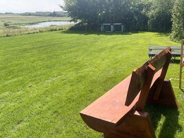 Un espacio al aire libre con césped, un banco de madera y una mesa de picnic.