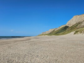 Una playa de guijarros con cielo despejado y acantilados al fondo.