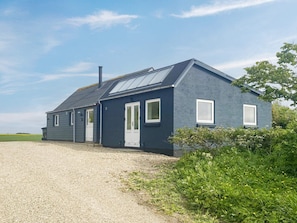 A modern house with a gravel driveway, a chimney, and a large window. - 4 Person Holiday Home in Lemvig (Lemvig)