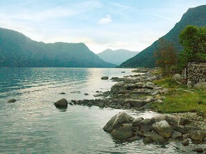 A rocky shoreline with a stone wall and a mountain backdrop.