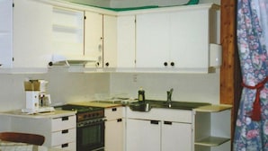 A compact kitchen with white cabinets, a stove, a sink, and a coffee maker. - 4 Person Holiday Home in Høyheimsvik (Luster)