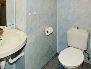 A bathroom with a sink, toilet, and a toilet paper holder on the wall.