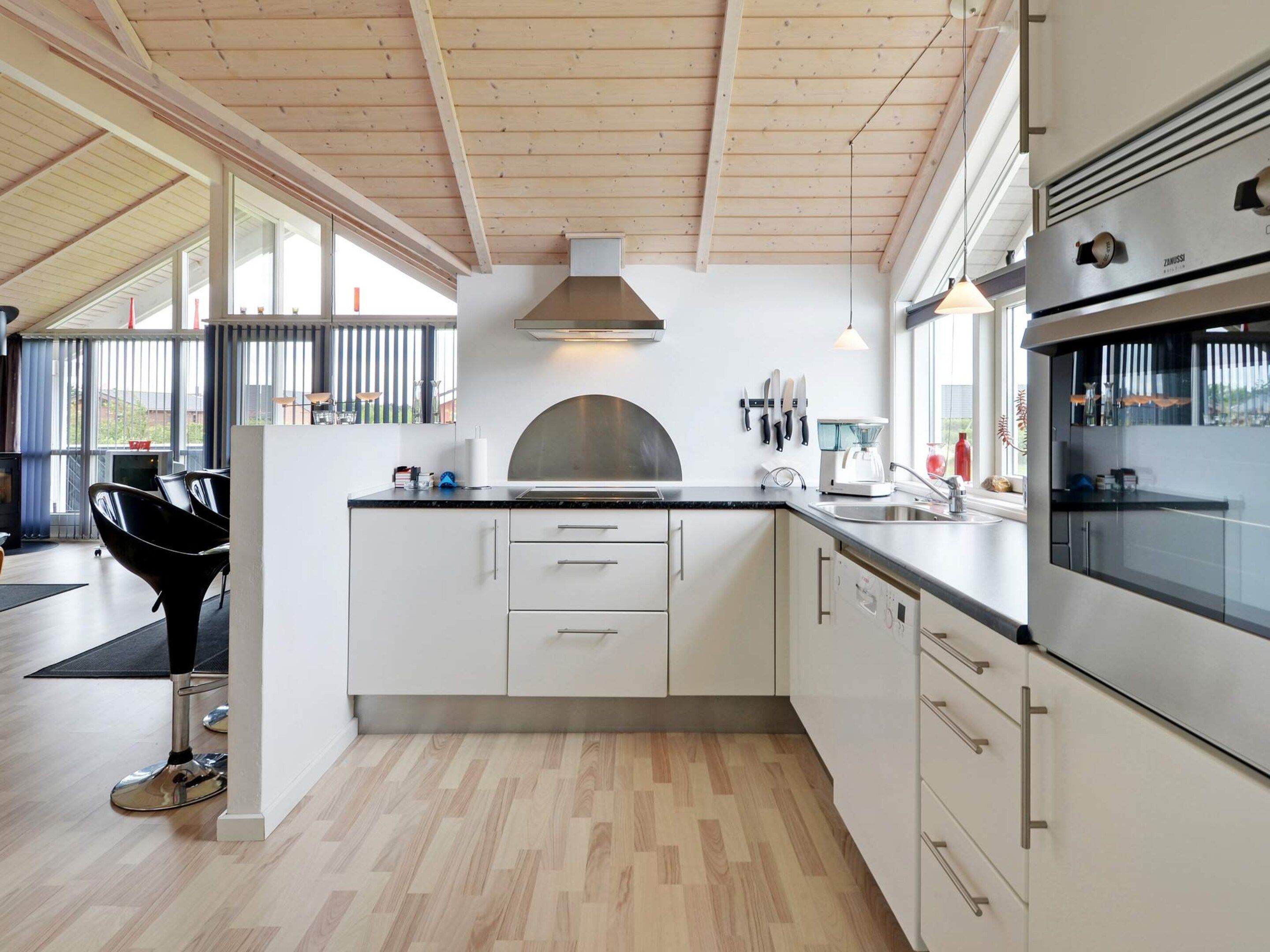 A modern kitchen with white cabinetry, a black countertop, and a large window providing natural light.