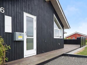 Un bâtiment noir avec une porte et une fenêtre blanches, une boîte aux lettres et un panneau portant le chiffre « 6 ».